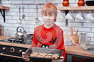 Redhaired child boy bake cookies for Christmas. Merry Christmas and Happy Holidays