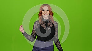 Redhaired girl begins to dance, she is in a good mood. Green screen