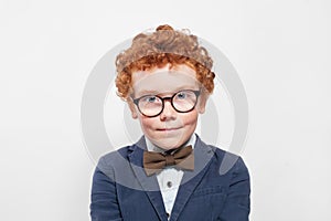 Redhead boy in blue suit with bow tie on white
