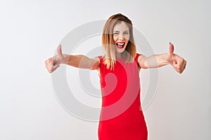 Redhead businesswoman wearing elegant red dress standing over isolated white background approving doing positive gesture with