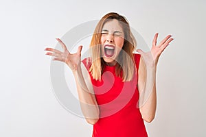 Redhead businesswoman wearing elegant red dress standing over isolated white background celebrating mad and crazy for success with