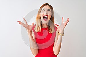 Redhead businesswoman wearing elegant red dress standing over isolated white background crazy and mad shouting and yelling with