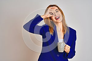 Redhead caucasian business woman drinking a cup of coffee over isolated background with happy face smiling doing ok sign with hand