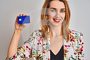 Redhead caucasian business woman holding credit card over isolated background with a happy face standing and smiling with a