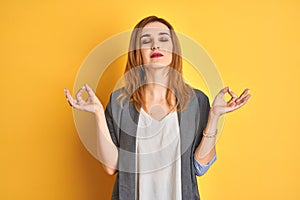 Redhead caucasian business woman over yellow isolated background asking to be quiet with finger on lips