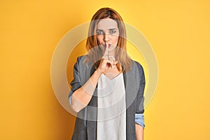 Redhead caucasian business woman over yellow isolated background looking at the camera blowing a kiss on air being lovely and sexy