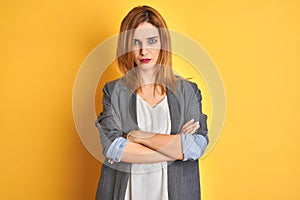 Redhead caucasian business woman over yellow isolated background shouting suffocate because painful strangle