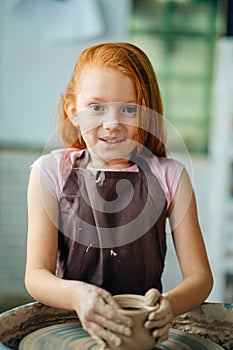 Redhead Child sculpts from clay pot. workshop on modeling on potter`s wheel.