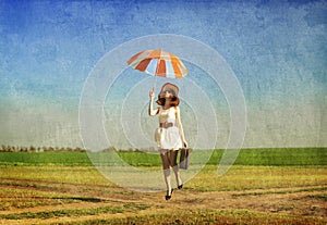 Redhead enchantress with umbrella and suitcase at spring country