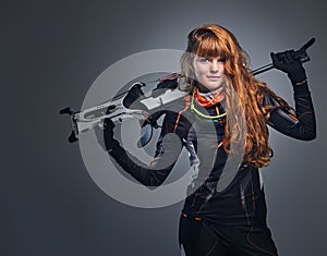 Redhead female Biathlon champion aiming with a competitive gun.