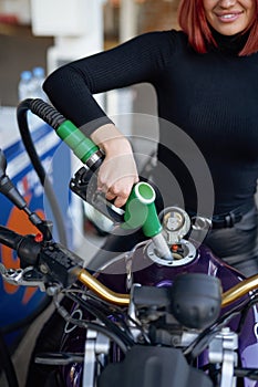 Redhead female driver fueling own bike in service