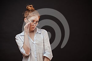 Redhead female model in glasses posing on black background