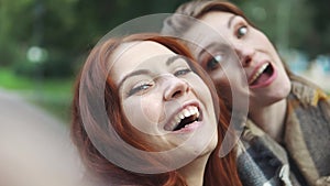 Redhead friends taking selfie with a smart phone and making faces and fun