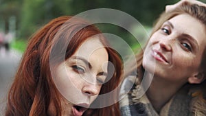 Redhead friends taking selfie with a smart phone and making faces and fun.