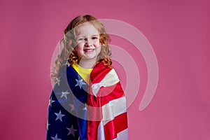 Redhead ginger charming female kid celebration independence holding american flag on a pink background in the studio