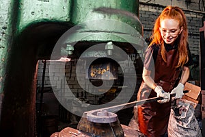 Redhead ginger woman working smithytools in dark workplace forging hammering malleation details. small business concept