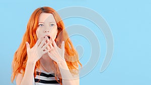 Redhead girl covers her mouth with her hand. Surprise and shock
