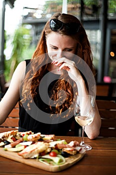 Redhead girl eating and drinking wine in restaurant