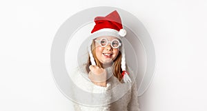 Redhead girl with freckles shows yes, behaved well and receives a gift from Santa Claus, isolated on a white background