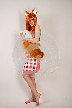 Redhead girl with fur ears and tail posing in kitchen apron on white background in Studio