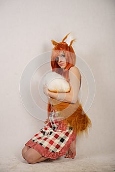 Redhead girl with fur ears and tail posing in kitchen apron on white background in Studio