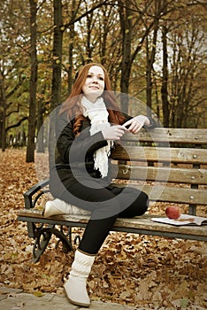 Redhead girl with headphones listen music on player in city park, fall season