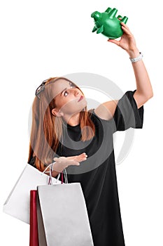 Redhead girl holding shopping bags and an empty piggy bank