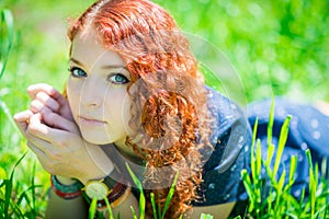 Redhead girl lay on grass.