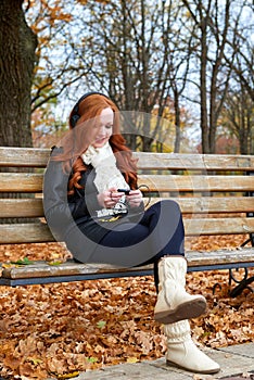 Redhead girl listen music in city park, fall season