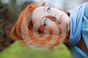 Redhead girl looking up lying down on green