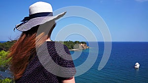 Redhead girl looks from a hill on the Mediterranean Sea with a yacht in Phaselis. City of ancient Lycia. Turkey.