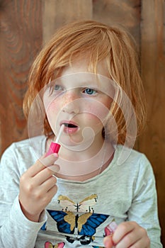 The girl paints lips with brilliance