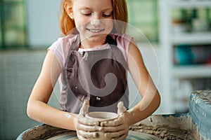 Redhead Child sculpts from clay pot. workshop on modeling on potter`s wheel.