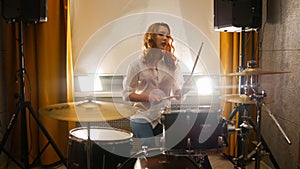 Redhead girl sits behind a drum set in the studio