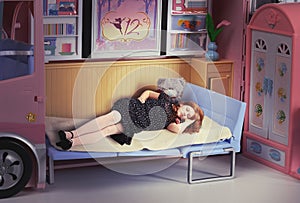 Redhead girl sleeping in a doll bed