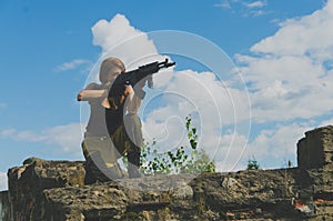 Redhead girl stands on one knee and aim from the weapon