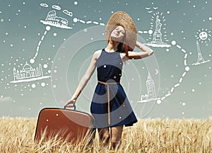 Redhead girl with suitcase at spring wheat field.