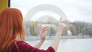 Redhead girl touches glass