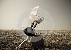 Redhead girl with umbrella at windy field.