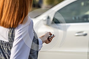 Redhead girl unlocking a car with wireless key