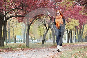 Redhead girl walk on pathway in city park, fall season