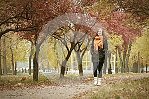 Redhead girl walk on pathway in city park, fall season