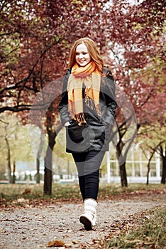 Redhead girl walk on pathway in city park, fall season