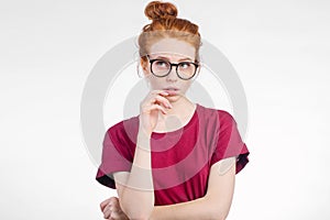 Redhead girl wearing glasses with hair knot and freckles looking sideways