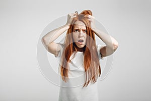 Redhead girl on white background with strong expression of fear, round eyes