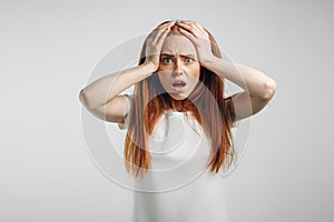 Redhead girl on white background with strong expression of fear, round eyes