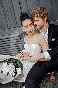 redhead groom hugging african american bride