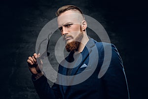 Redhead male dressed in a blue suit and sunglasses.