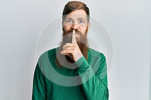 Redhead man with long beard wearing casual clothes asking to be quiet with finger on lips