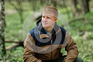 Redhead man sits in spring forest